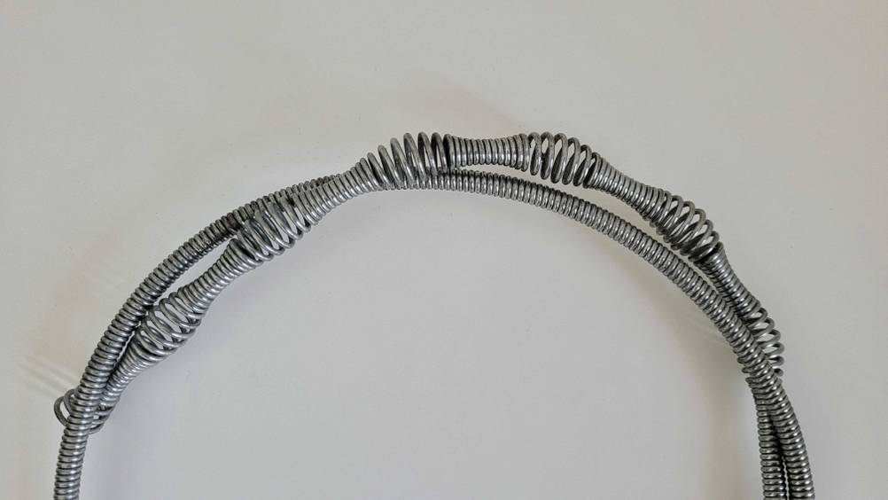 Nahaufnahme einer getesteten Rohrreinigungsspirale mit größeren und kleineren Schlingen.