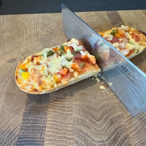 Mit einem Messer wird ein Baguette geschnitten