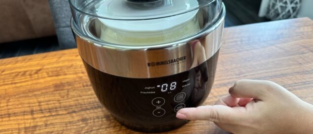 Eine Hand drückt auf den Start/Stopp-Knopf des Rommelsbacher Joghurt- und Frischkäsezubereiter JG80 Jona