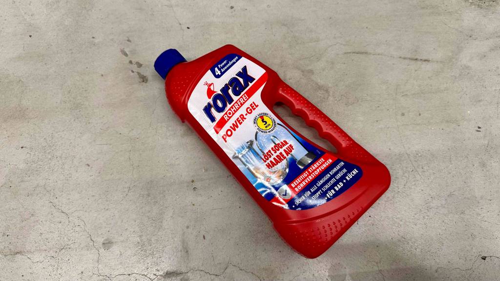 Eine Flasche mit getestetem Rohrreiniger liegt auf einem Betonboden.