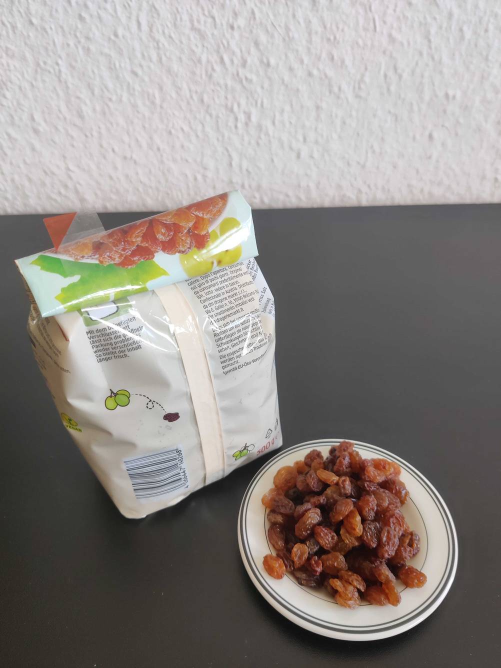 In einer Schüssel befinden sich getestete Rosinen neben der Verpackung. 