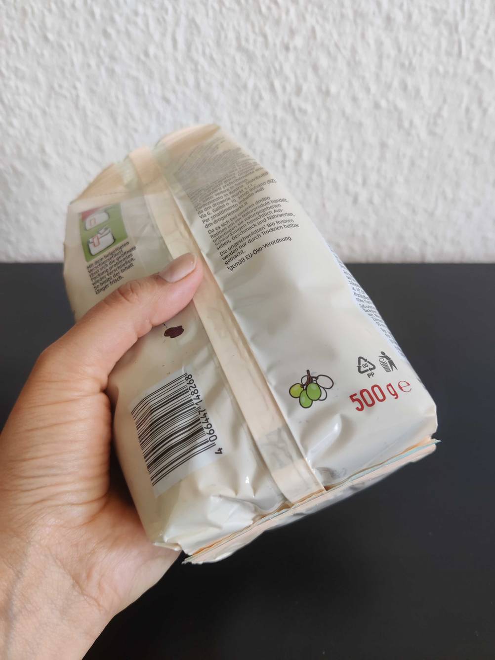 Eine Hand hält eine getestete Rosinen-Packung. 