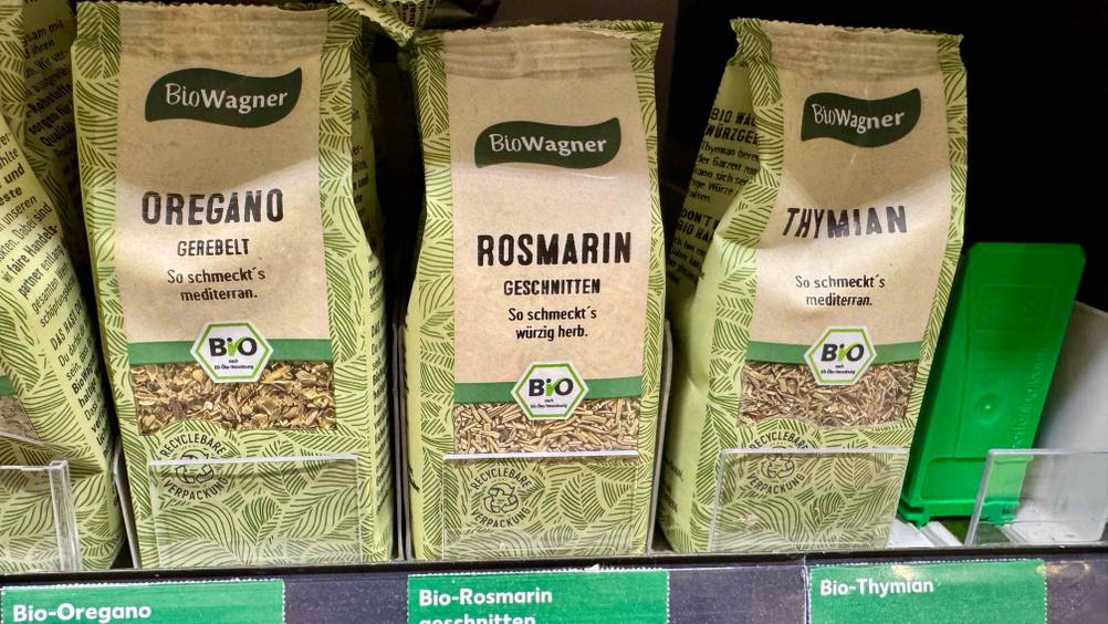 Mehrere Packungen des getesteten Rosmarins stehen in einem Verkaufsregal neben anderen Produkten.
