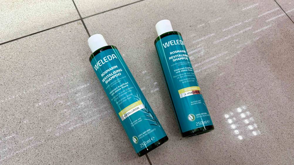 Rosmarin-Shampoo im Test: Zwei Flaschen liegen nebeneinander auf einem Fließenboden.