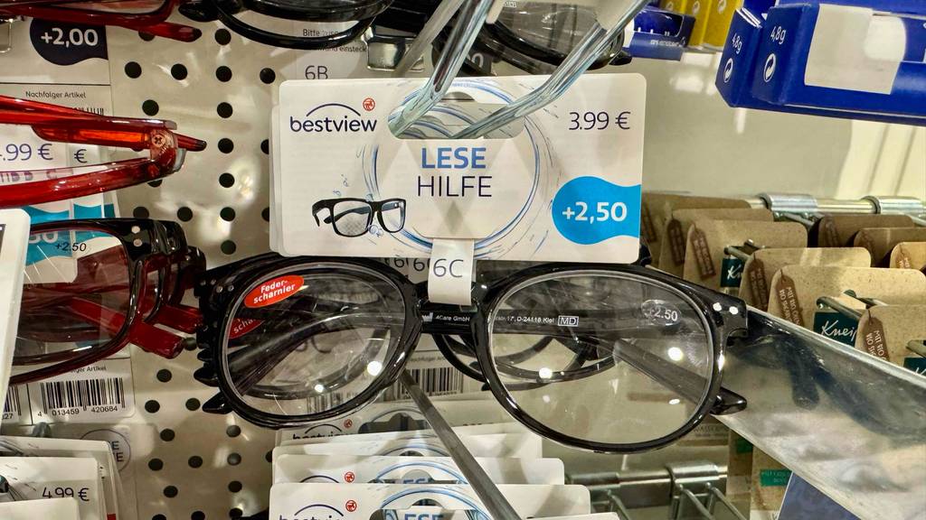 Eine Lesehilfe im Test hängt in einem Verkaufsregal neben Lesebrillen.