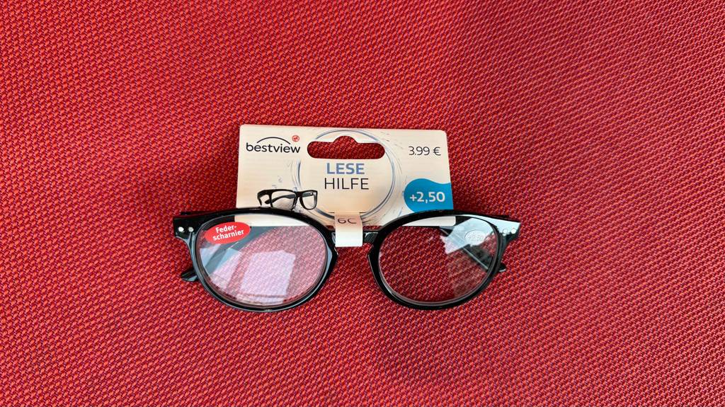 Eine getestete Lesehilfe mit Federscharnier liegt auf einem roten Stoff.