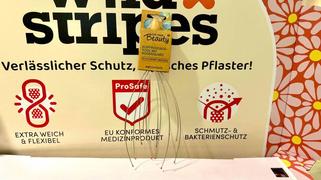 Eine Kopfmassage-Spinne steht zum testen vor einem Textplakat.
