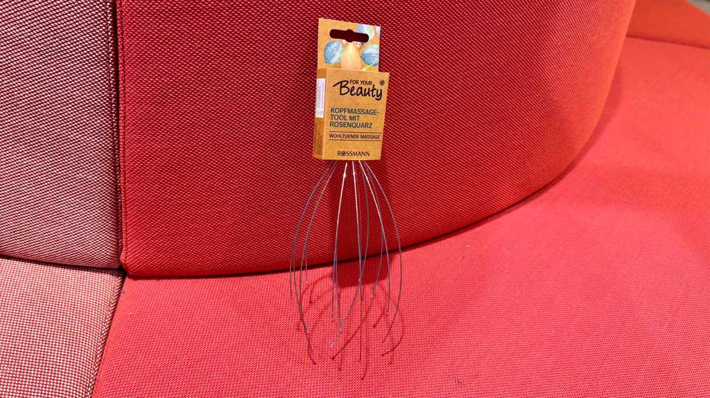 Eine getestete Kopfmassage-Spinne lehnt an eine rote Couch.