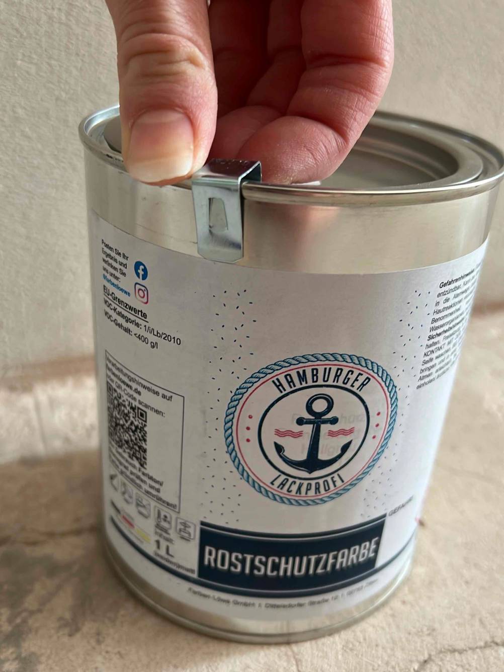 Eine Hand öffnet eine getestete Rostschutzfarbe-Verpackung. 