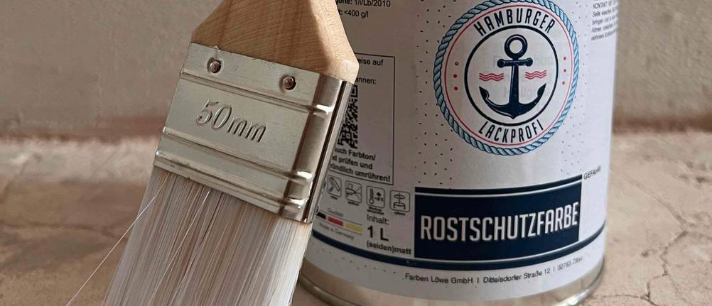 Eine Packung Rostschutzfarbe und ein weißer Pinsel