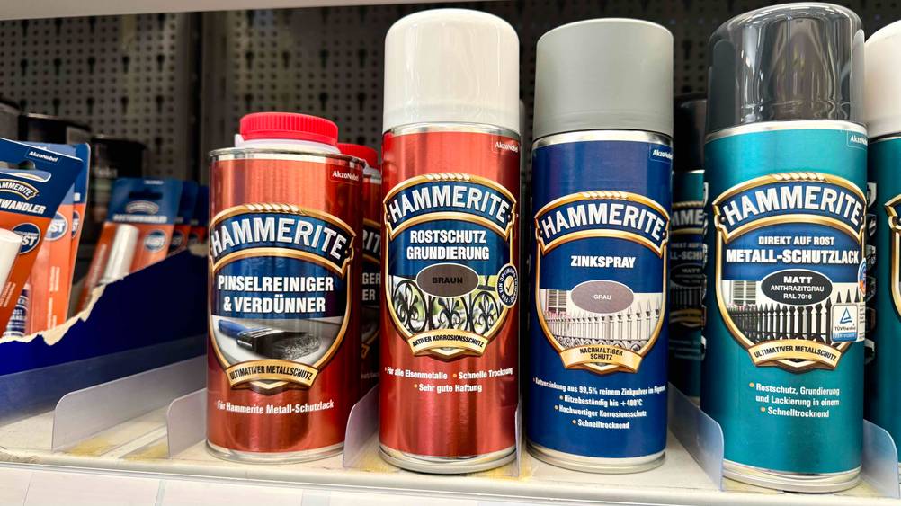 Mehrere Dosen der getesteten Rostschutzgrundierung in einem Verkaufsregal neben anderen Produkten.