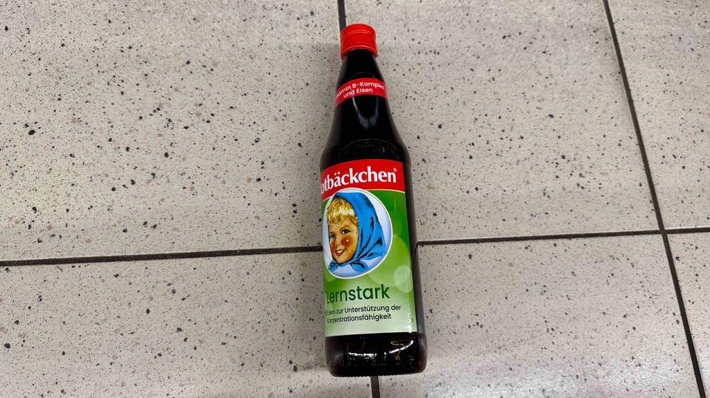 Eine Flasche mit getestetem Eisensaft von Rotbäckchen liegt auf dem Boden.