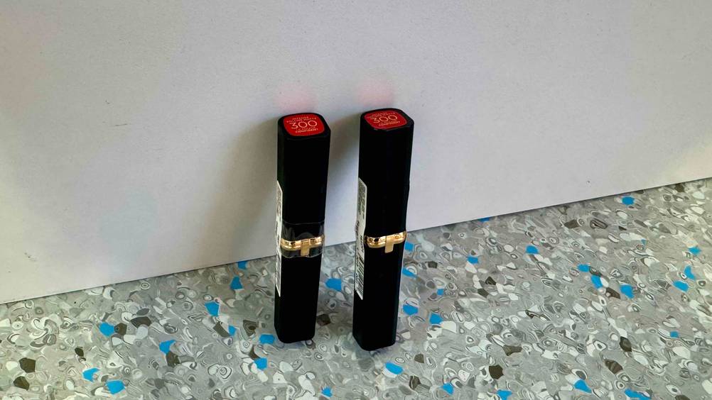 Roter Lippenstift-Test: Zwei Stifte von schräg oben vor einer hellen Wand auf dem Boden stehend.