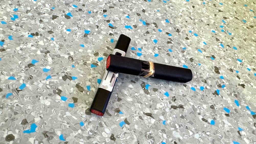 Roter Lippenstift getestet: Zwei Stifte leicht übereinander auf einem grau-blauen Boden.