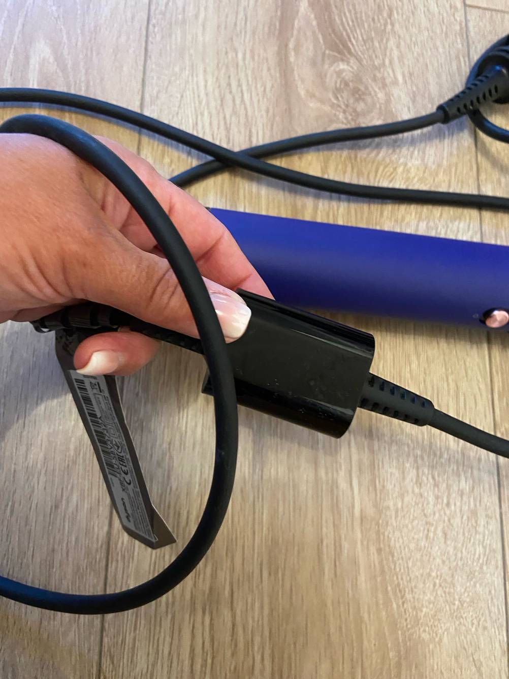Eine Hand hält das Kabel der getesteten rotierenden Warmluftbürste.