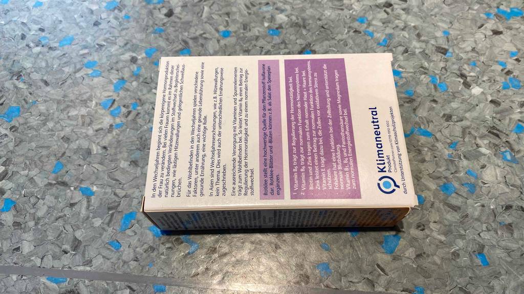 Rückseite der Verpackung von getesteten Rotklee-Kapseln auf einer grauen Fläche.