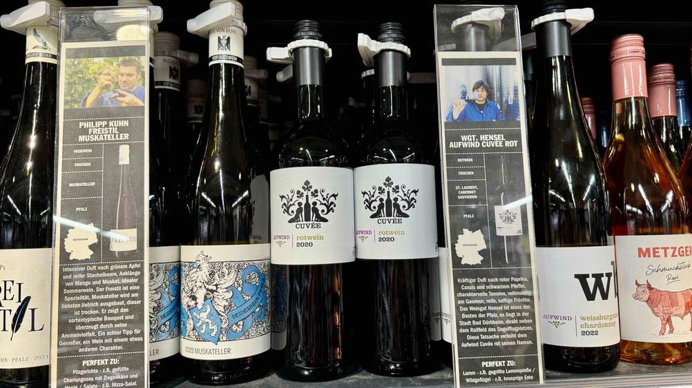 Mehrere Flaschen des Rotwein (Deutschland) im Test in einem Verkaufsregal neben anderen Produkten.