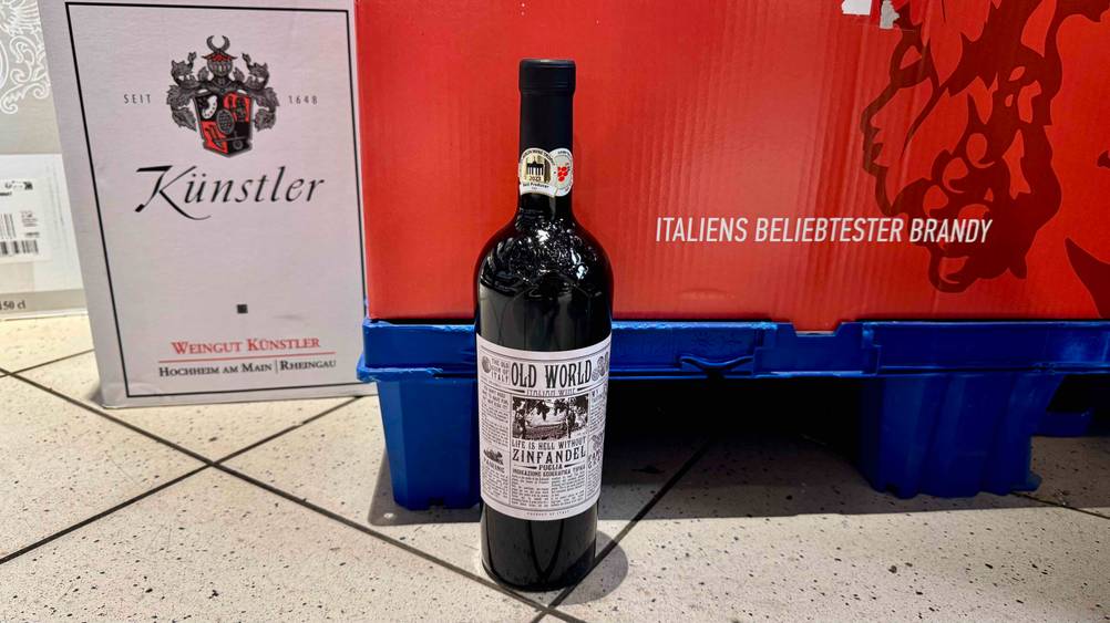 Rotwein (halbtrocken)-Test: Eine Flasche von vorne vor einer Plastikpalette auf dem Boden.