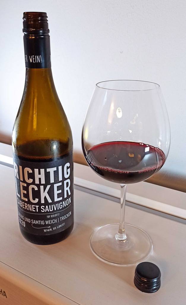 Rotweinglas von Ikea mit etwas Wein neben Flasche.