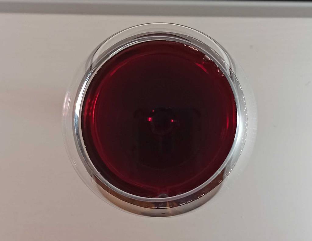 Rotweinglas von oben mit Wein gefüllt.