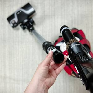 Eine Hand führt die Easy Brush des Rowenta RO7649EA Richtung Teleskoprohr. Der Staubsauger ist im Hintergrund zu sehen.