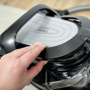 Eine Hand öffnet den Staubbehälterdeckel des Rowenta RO7954. Der Behälterdeckel ist mit dem Schriftzug „Open“ markiert.