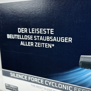 Die Verpackung des Rowenta RO7954 trägt den Werbeslogan „Der leiseste beutellose Staubsauger aller Zeiten“. Die Verpackung ist in Blau-Weiß gestaltet.