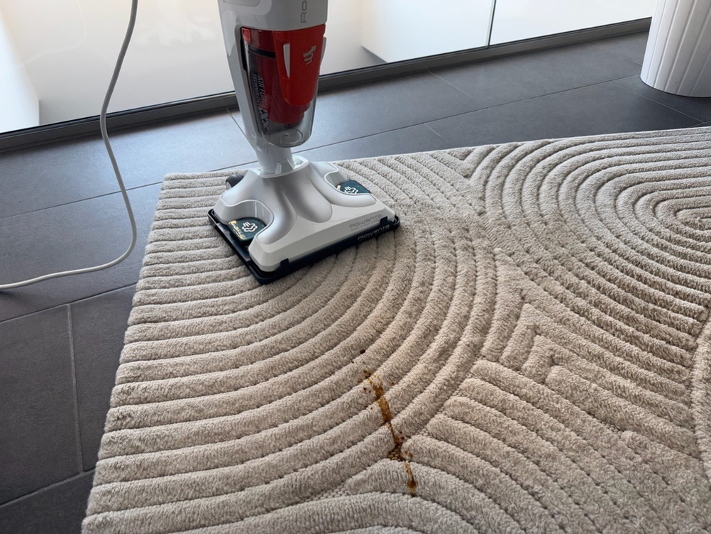 Rowenta RY8544 steht auf dem Teppich, davor ein großer Kaffeefleck