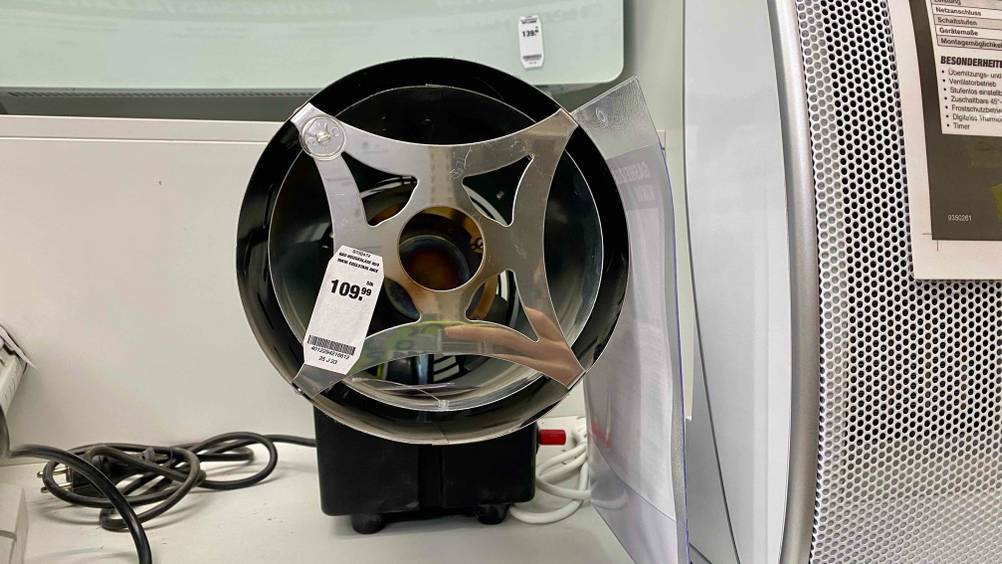 Ansicht in das Innere eines Gasheizstrahlers im Test, der aus einem Metall-Zylinder besteht und auf einer schwarzen Elektro-Basis mit rotem Einschalthebel platziert ist.