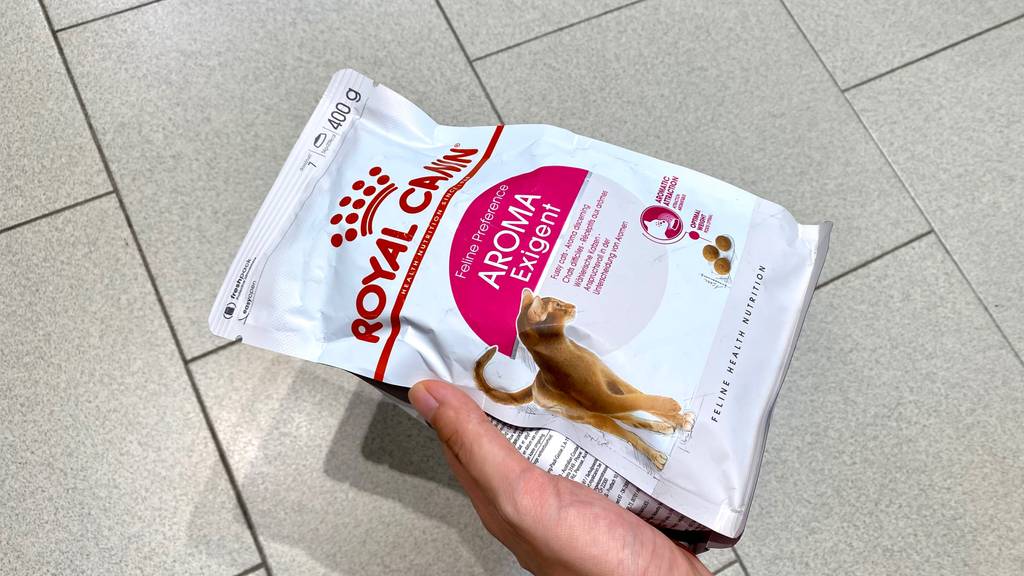 Im Test: Hand hält eine Packung Royal Canin Katzenfutter über hellen Fliesen.