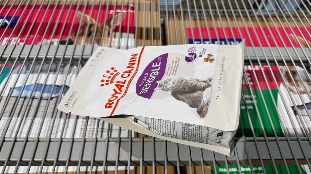 Verpacktes Katzenfutter sensitive liegt zum testen quer in einem Gitterregal.