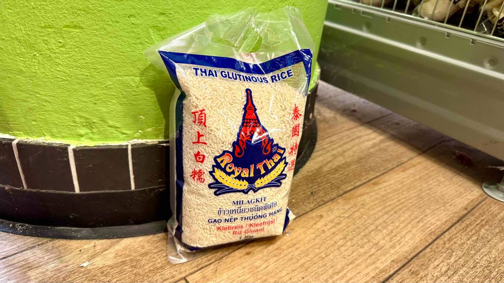 Eine Packung getesteter Thai-Reis steht vor einer schwarz-grünen Wand.