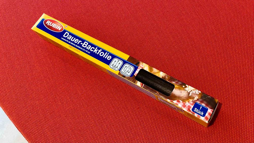 Im Test: Eine Dauerbackfolie in Originalverpackung liegt auf einem roten Polster.