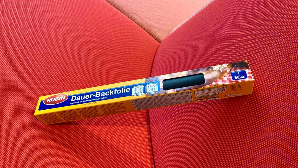 Eine getestete Dauerbackfolie in Originalverpackung leicht aufgestellt auf einem roten Polster.