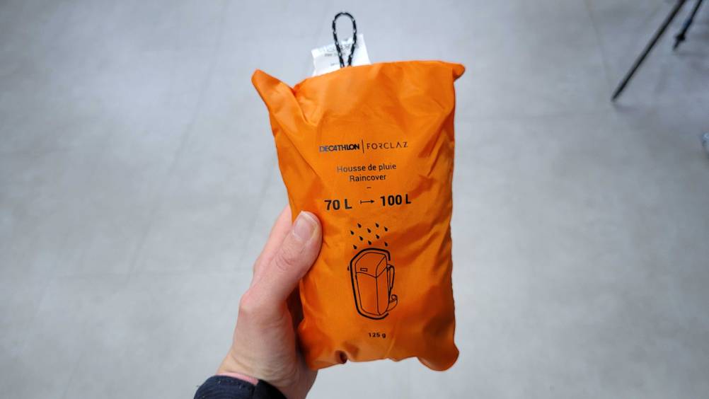 Eine Hand hält den getesteten Rucksack-Regenschutz hoch.