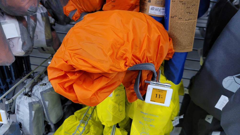 Ein aufgefalteter Rucksack-Regenschutz im Test in einem Verkaufsregal.