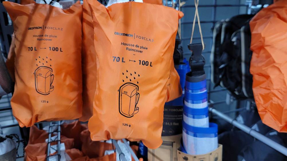 Mehrere der getesteten Rucksack-Regenschutze hängen in einem Regal.