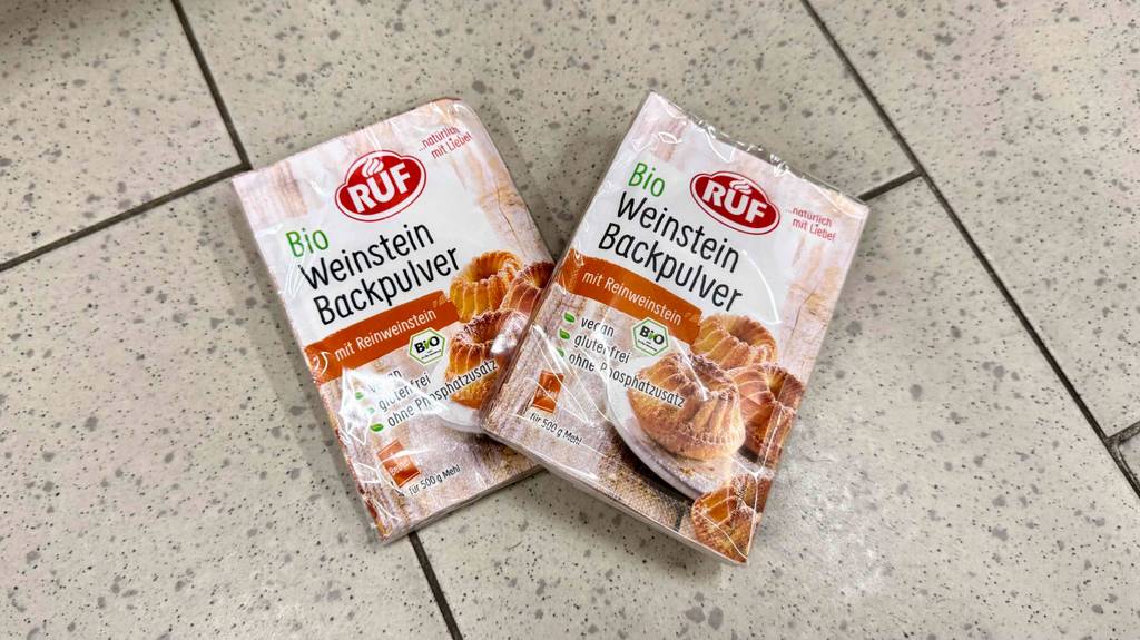 Zwei Packungen mit Bio-Weinsteinbackpulver im Test liegen auf einem Fliesenboden.
