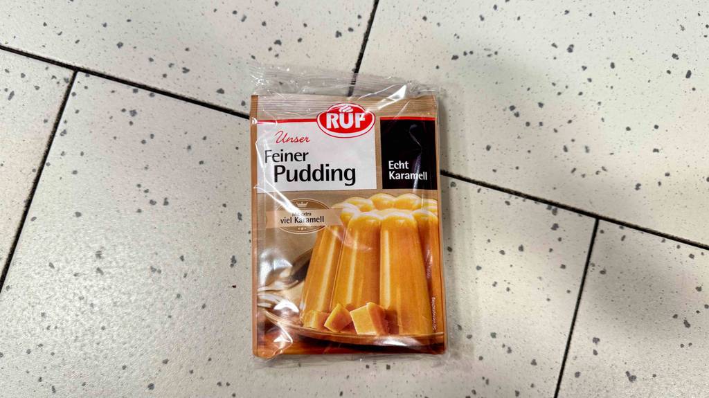 Eine Packung mit getestetem Puddingpulver der Marke RUF liegt auf einem Fliesenbelag.