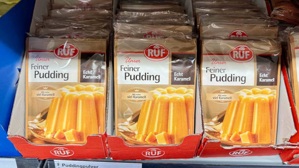 Puddingpulver-Test: Mehrere versiegelte Packungen der Marke RUF befinden sich in einem Karton auf einem Verkaufsregal.
