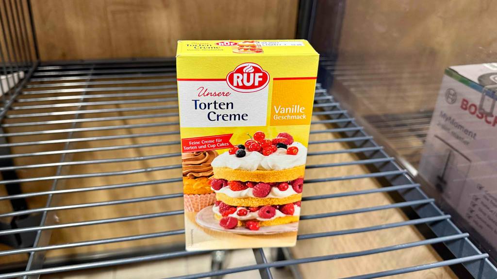 Eine Packung Tortencreme steht zum testen in einem Gitterregal.