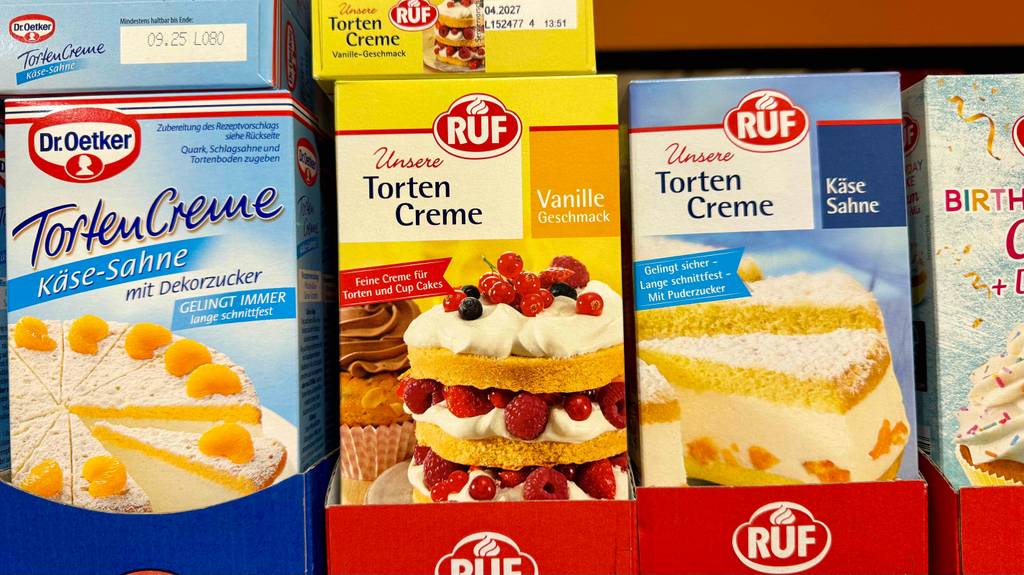 Tortencreme im Test: Mehrere Packungen unterschiedlicher Geschmacksrichtungen stehen hinter- und nebeneinander in einem Regal.