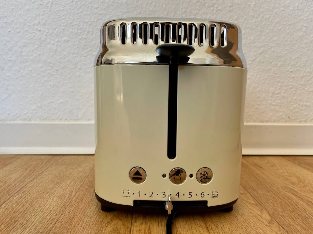 Seitenansicht eines cremefarbenen, getesteten Retro-Toasters mit Lifthebel und weiteren Funktionstasten.