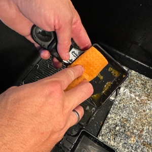 Eine Raclettepfanne des Russell Hobbs 26280-56 wird mit einem Lappen gereinigt.