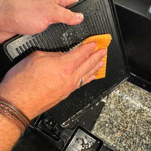 Die Grillplatte des Russell Hobbs 26280-56 wird mit einem Lappen gereinigt.