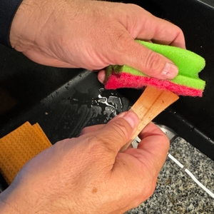 Ein Raclettespachtel des Russell Hobbs 26280-56 wird mit einem Schwamm gereinigt.