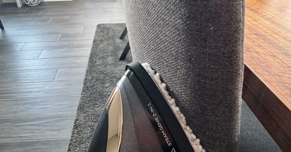 Die Stofflehne eines Stuhl wird mit dem Dampfglätter bearbeitet.