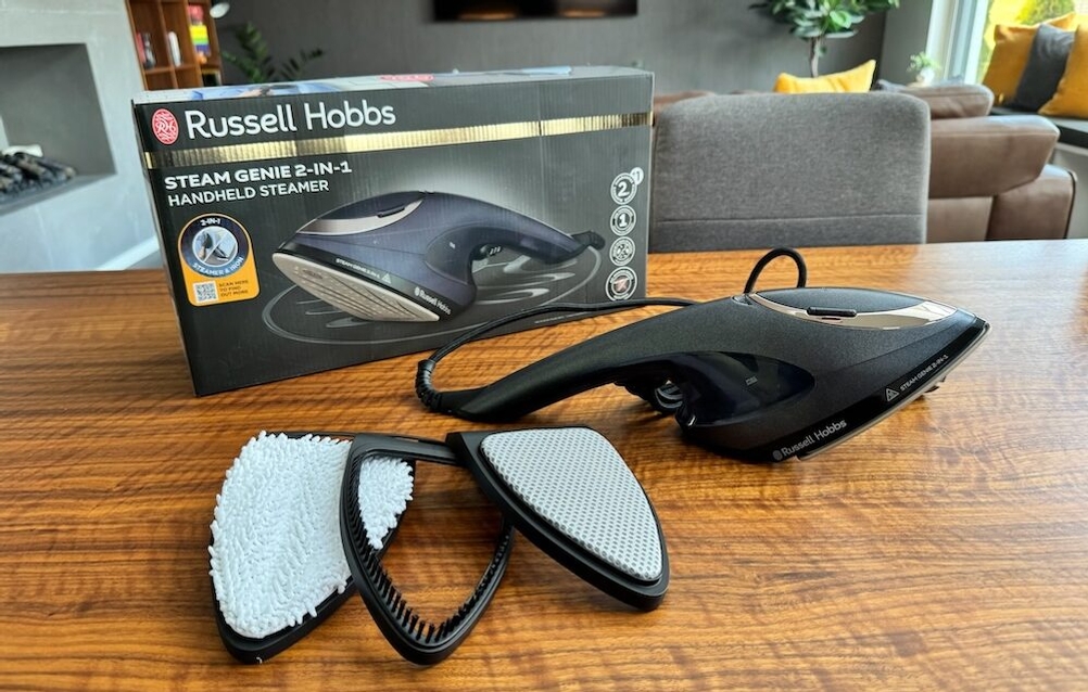 Der Russel-Hobbs-Dampfglätter liegt samt Zubehör auf einem Tisch.