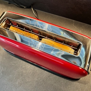 Eine Scheibe Vollkorntoast und Weizentoast stehen während des Toastens im Russell Hobbs Colours Flame Red.