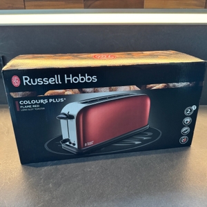 Der geschlossene Karton des Russell Hobbs Colours Flame Red steht auf einer Küchenarbeitsplatte.